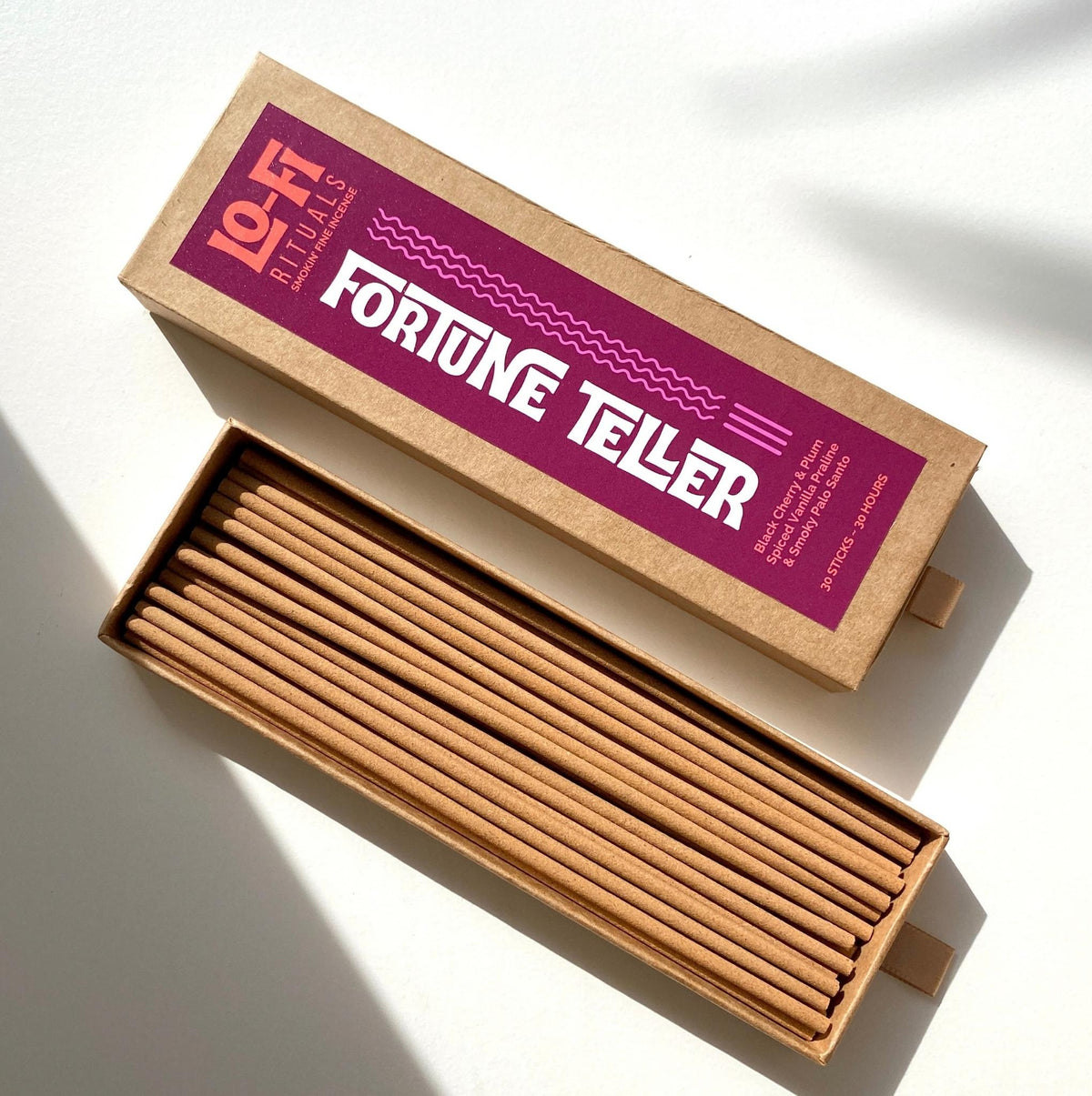 An open box of Lo-Fi Rituals Fortune Teller Incense in the sun on a white background with shadows