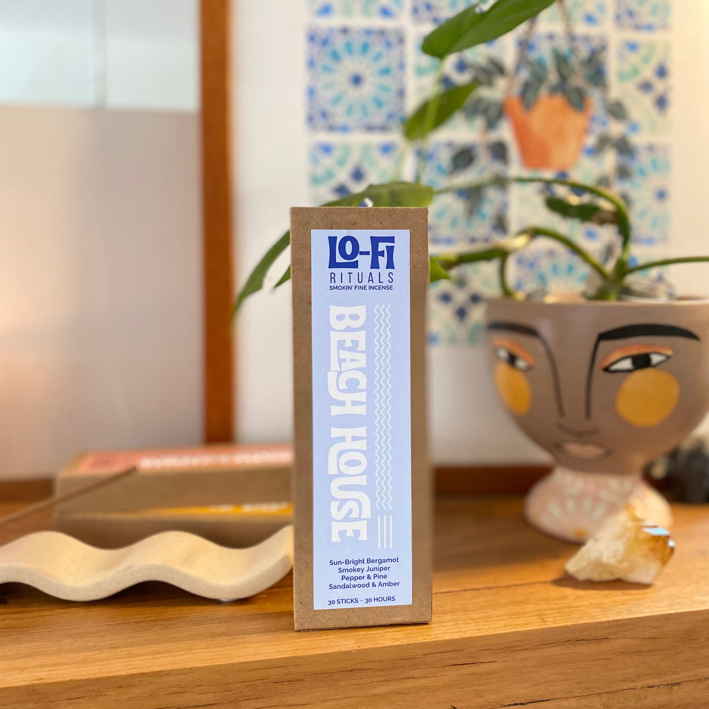 Lo-Fi Rituals 'Beach House' incense packaging front on centre on a timber surface with decorative elements in the background.