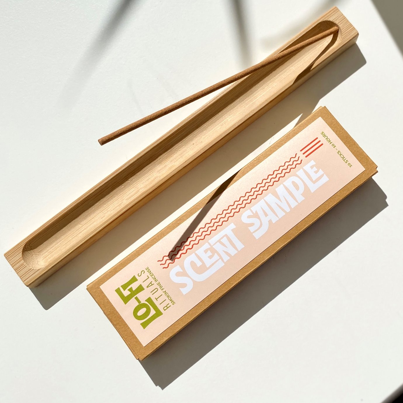 Wooden incense stick holder with a Lo-Fi Rituals incense sample box on a light sunlit background