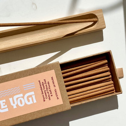 Open box of Lo-Fi Rituals Part-Time Yogi sandalwood incense sticks on a light background next to a wooden incense holder