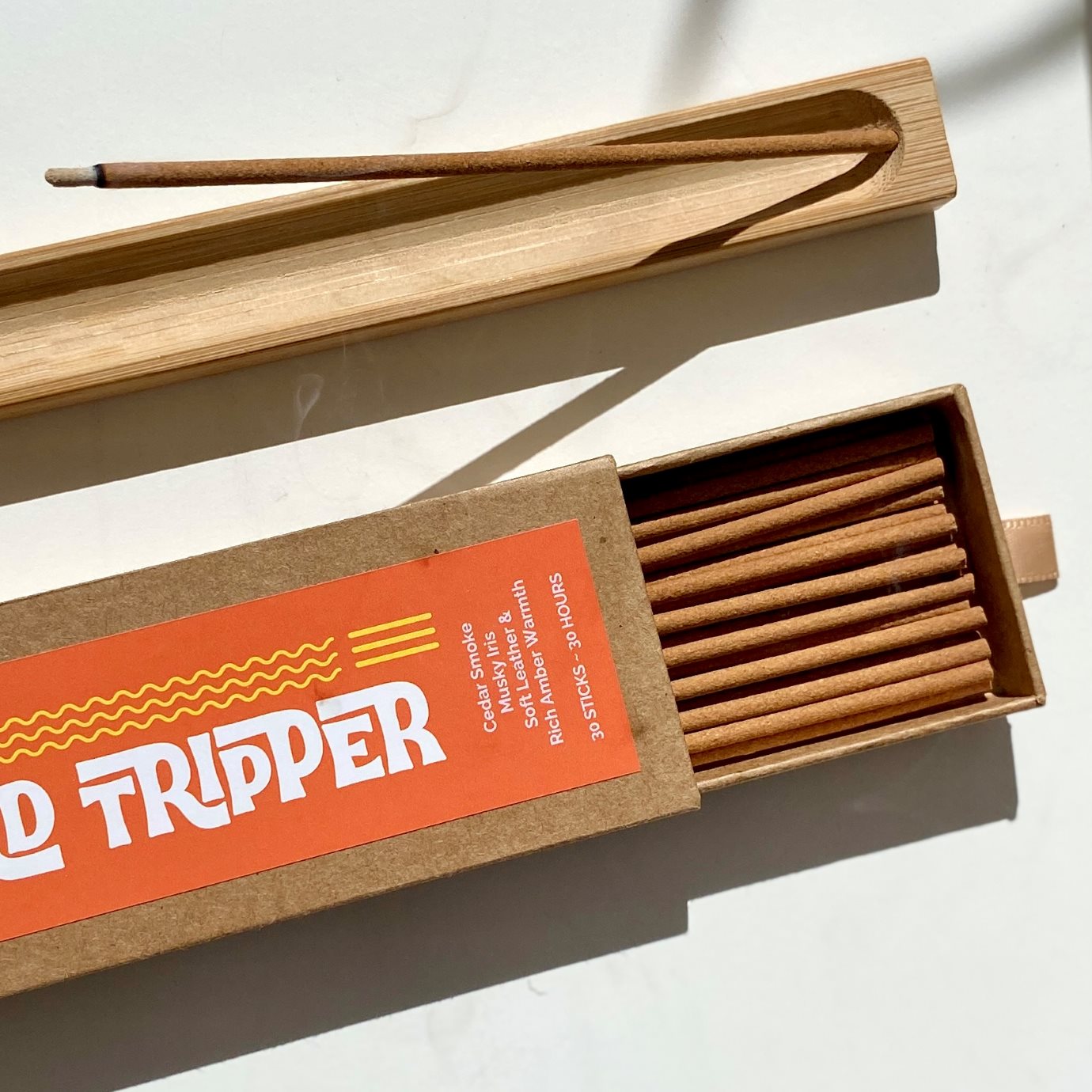 Incense sticks in an open kraft box labelled with Lo-Fi Rituals Road Tripper in bold, modern font on a sunlit light background.  