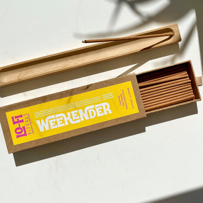 Open box of 'Lo-Fi  Rituals Weekender' incense sticks and wooden incense holder on a light background in full sun with cinematic shadows