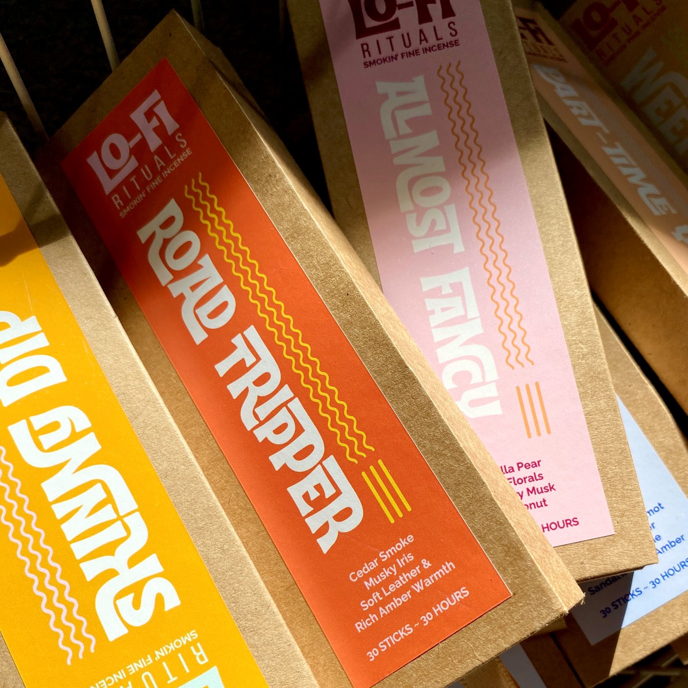 Three packages of Lo-Fi Rituals incense sticks with colorful bold labels, sitting askew in a bundle in the sunlight.