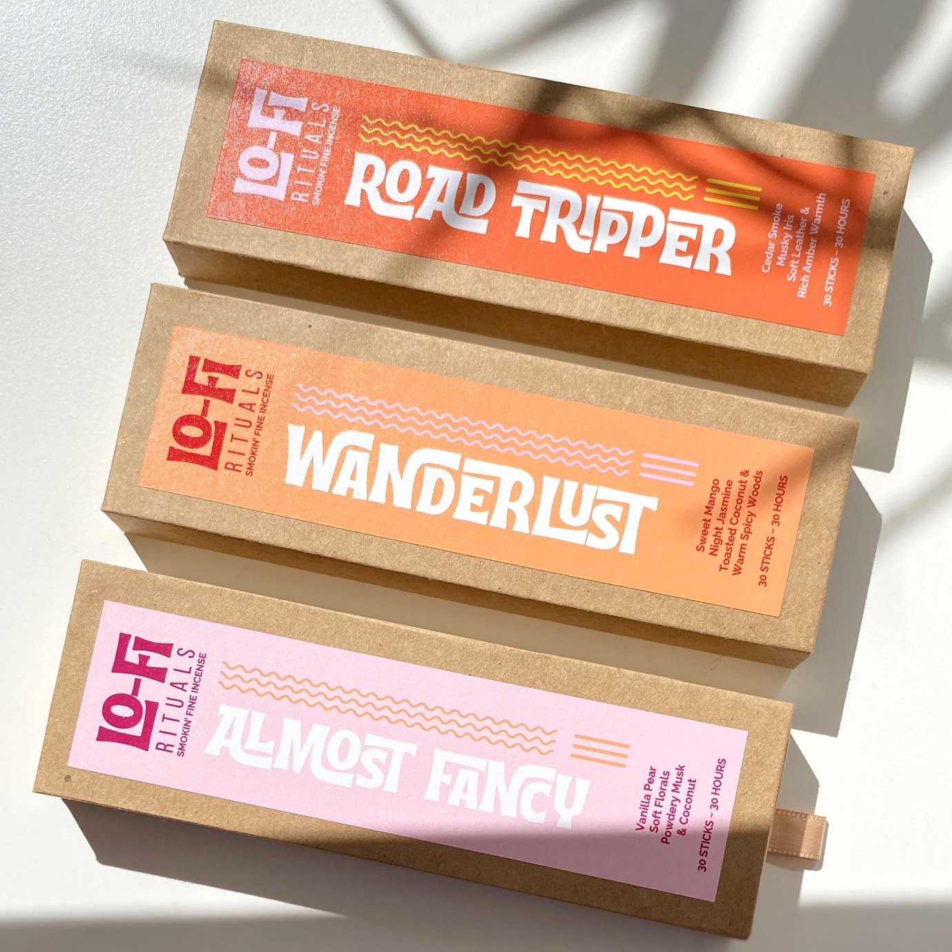 Three colourful boldly labelled Lo-Fi Rituals incense boxes on a sunlit white background with cinematic shadows